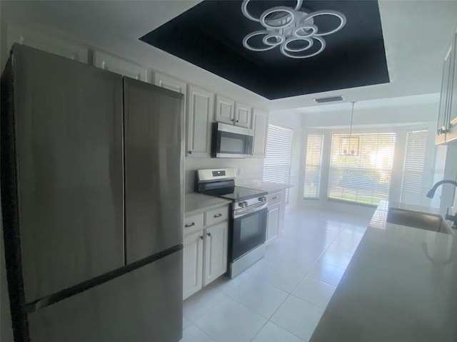 kitchen with white cabinets, stainless steel appliances, a raised ceiling, and sink