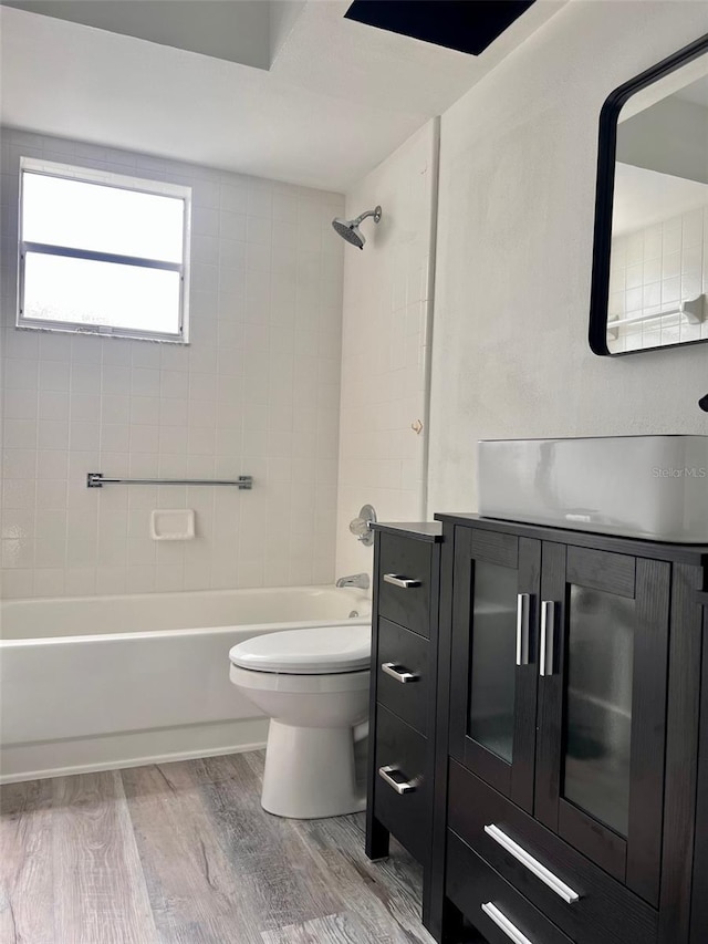 full bathroom featuring hardwood / wood-style floors, vanity, tiled shower / bath combo, and toilet