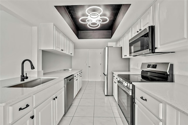 kitchen featuring sink, white cabinetry, a tray ceiling, stainless steel appliances, and light stone countertops