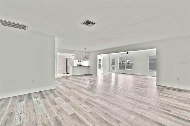 unfurnished living room featuring a healthy amount of sunlight, ceiling fan, and light wood-type flooring