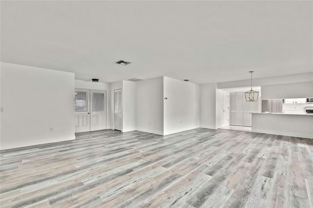 unfurnished living room featuring light hardwood / wood-style flooring and a notable chandelier