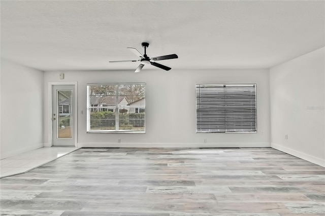 empty room with ceiling fan, a textured ceiling, and light hardwood / wood-style flooring