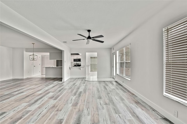 unfurnished living room with ceiling fan, light hardwood / wood-style floors, and a textured ceiling