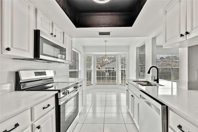 kitchen with appliances with stainless steel finishes, white cabinetry, sink, a raised ceiling, and light stone countertops