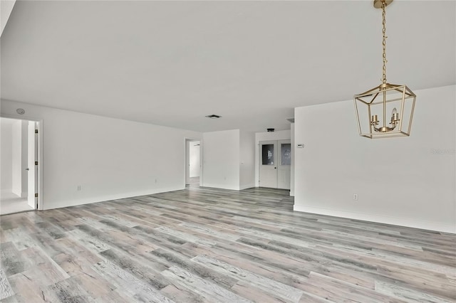 unfurnished living room featuring light hardwood / wood-style floors and a notable chandelier