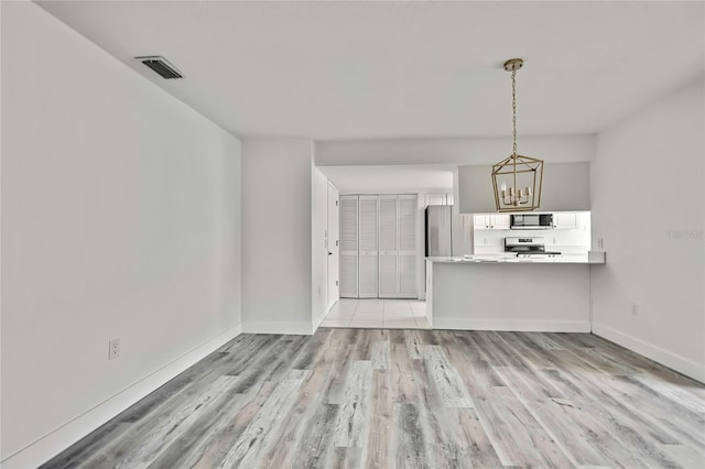 unfurnished living room with a notable chandelier and light wood-type flooring