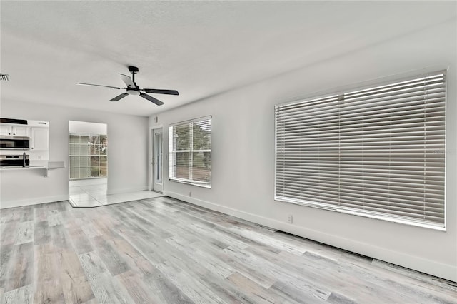 unfurnished living room with ceiling fan, light hardwood / wood-style flooring, and a textured ceiling