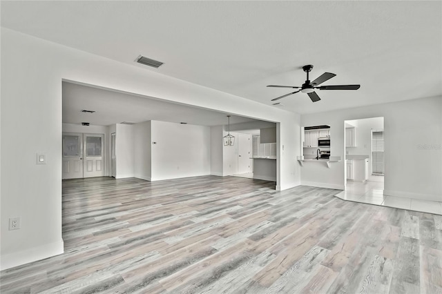 unfurnished living room featuring ceiling fan and light wood-type flooring