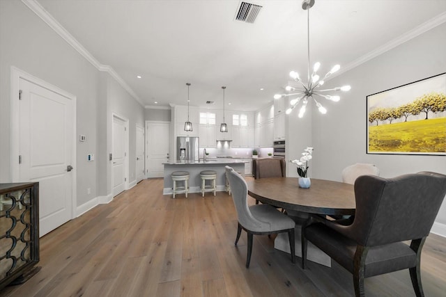 dining area featuring hardwood / wood-style floors, an inviting chandelier, ornamental molding, and sink