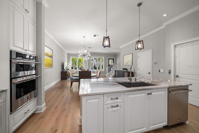 kitchen featuring light hardwood / wood-style floors, white cabinetry, an island with sink, and stainless steel appliances