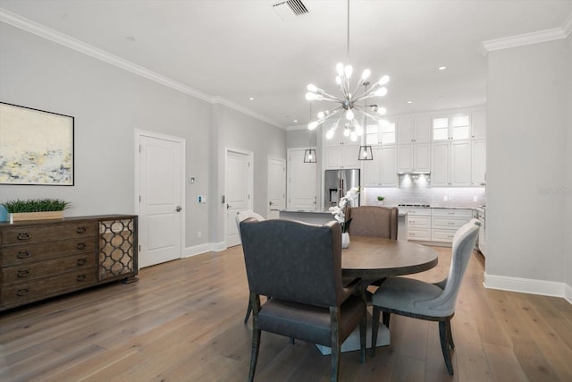 dining room featuring light wood-type flooring, crown molding, and a notable chandelier