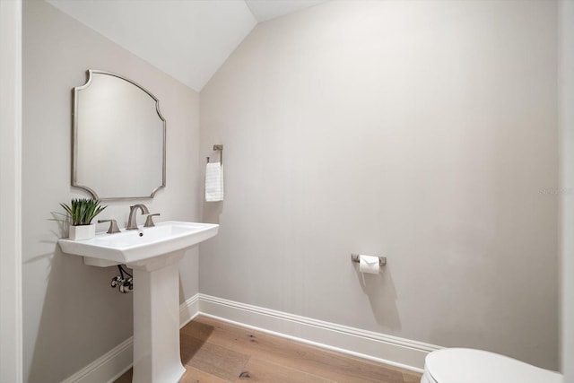 bathroom with toilet, wood-type flooring, and vaulted ceiling