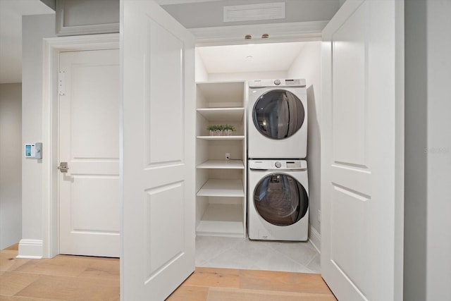 laundry area with stacked washer / dryer and light wood-type flooring