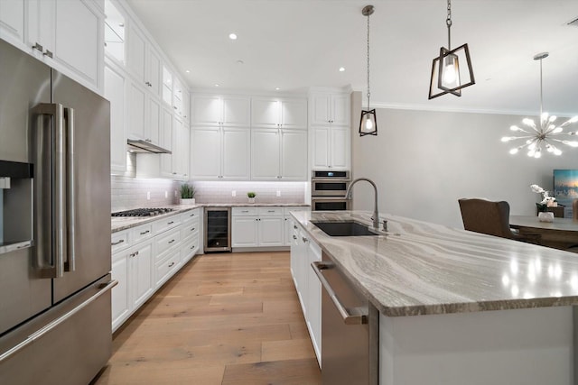 kitchen featuring sink, beverage cooler, an island with sink, white cabinets, and appliances with stainless steel finishes