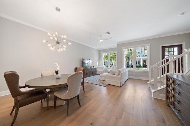 dining space with crown molding, light hardwood / wood-style floors, and ceiling fan with notable chandelier