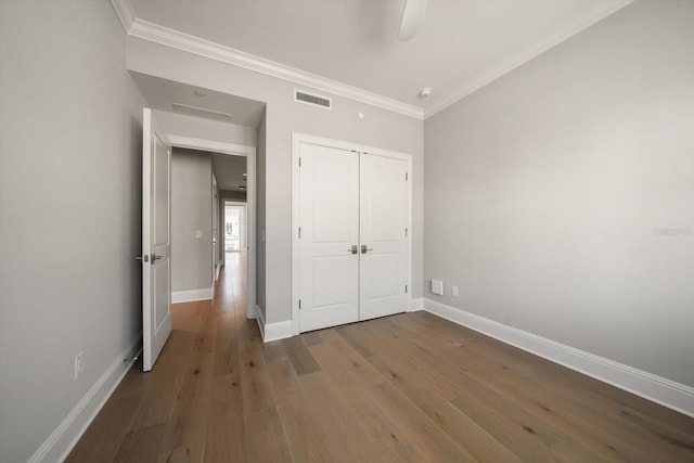 unfurnished bedroom featuring hardwood / wood-style flooring, ceiling fan, crown molding, and a closet