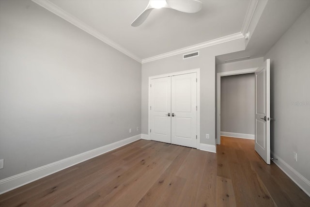 unfurnished bedroom with ceiling fan, dark hardwood / wood-style floors, crown molding, and a closet