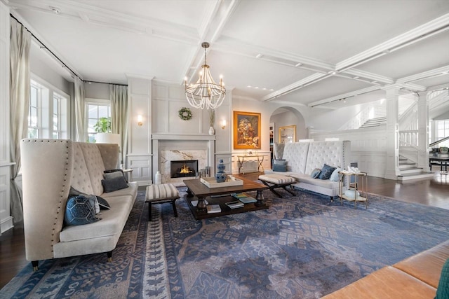 living room featuring coffered ceiling, beamed ceiling, hardwood / wood-style flooring, a fireplace, and ornamental molding