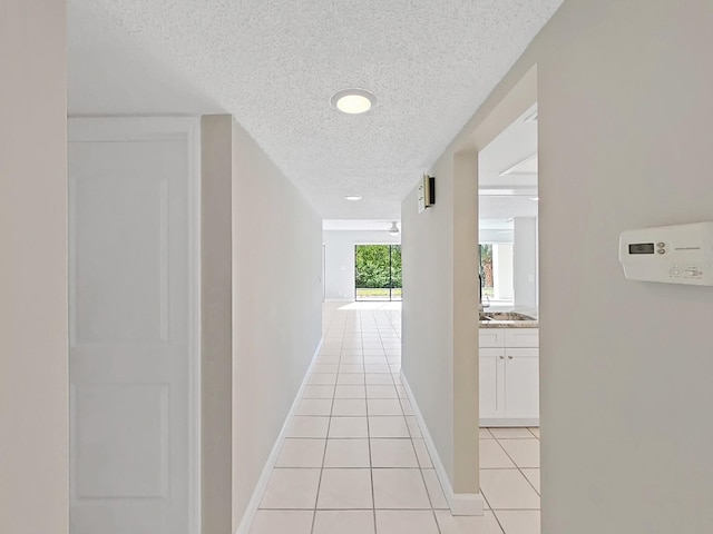 hall featuring light tile patterned flooring and a textured ceiling