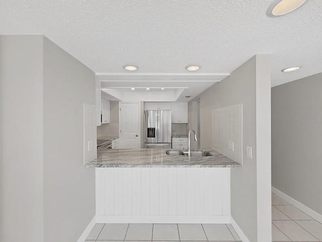 kitchen with white cabinetry, sink, stainless steel fridge with ice dispenser, kitchen peninsula, and a textured ceiling