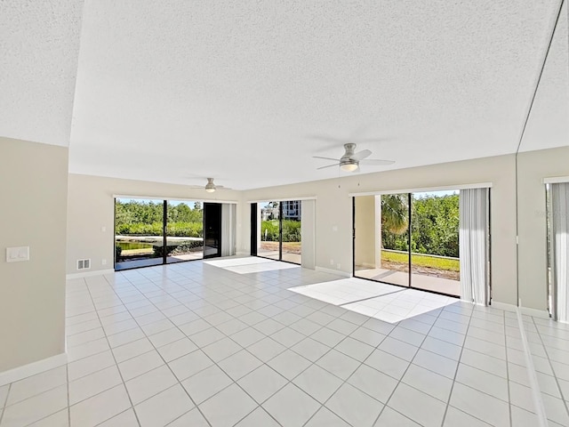 unfurnished living room with ceiling fan, a textured ceiling, plenty of natural light, and light tile patterned flooring