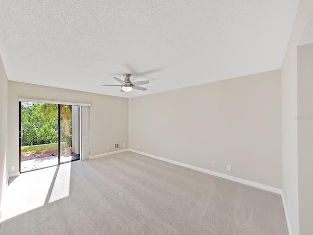 spare room featuring ceiling fan, light colored carpet, and a textured ceiling