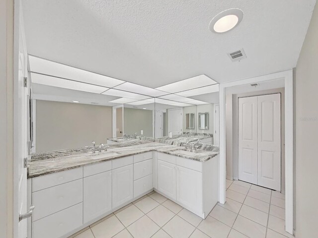 bathroom with tile patterned flooring, vanity, and a textured ceiling