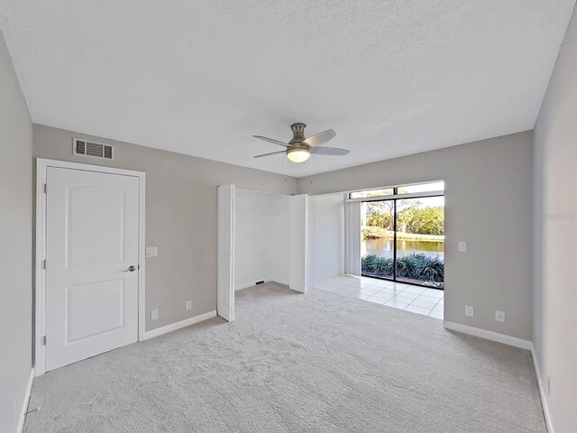 carpeted empty room with ceiling fan and a textured ceiling