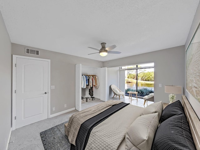 bedroom with access to exterior, a textured ceiling, light colored carpet, ceiling fan, and a closet