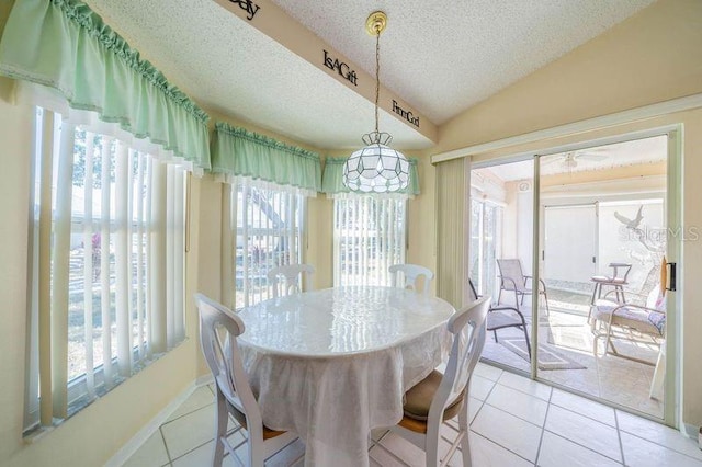 tiled dining area with a textured ceiling and vaulted ceiling