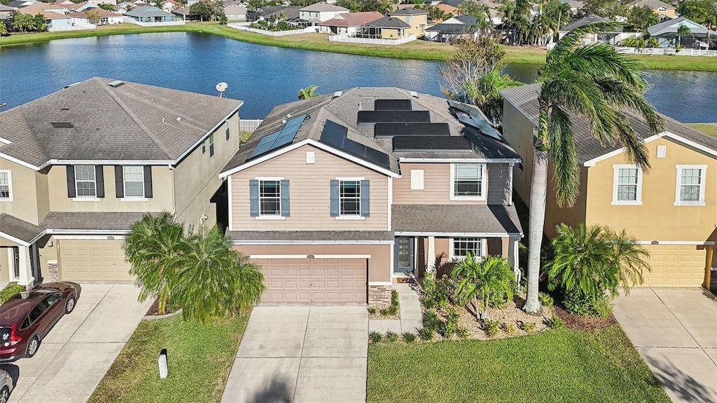 view of front facade with solar panels, a water view, a garage, and a front lawn