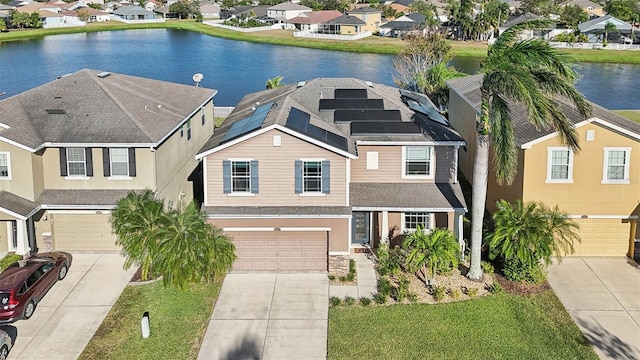 view of front facade with solar panels, a water view, a garage, and a front lawn