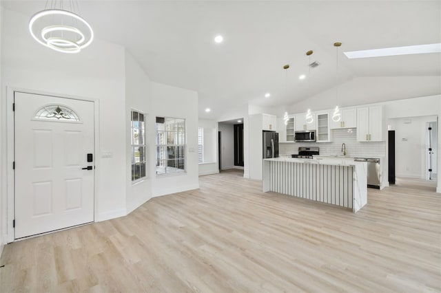 kitchen with white cabinetry, light hardwood / wood-style flooring, stainless steel appliances, and decorative light fixtures