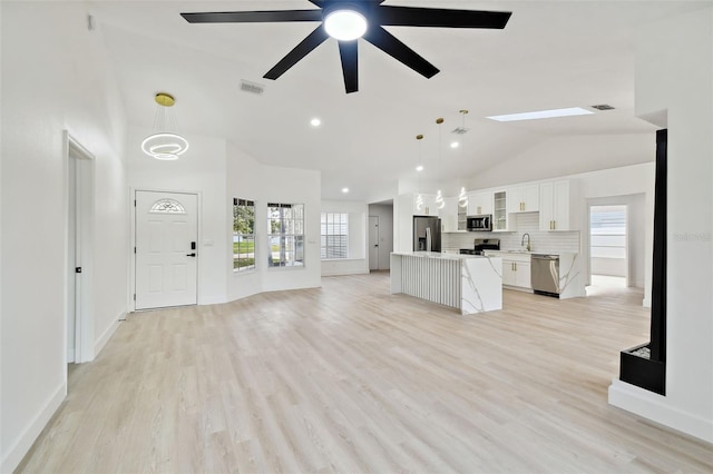 unfurnished living room with ceiling fan, sink, light hardwood / wood-style flooring, and vaulted ceiling