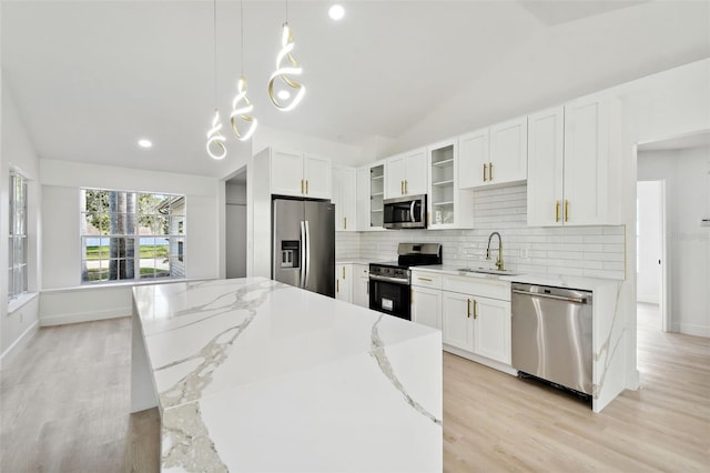 kitchen featuring light stone counters, stainless steel appliances, sink, pendant lighting, and white cabinetry