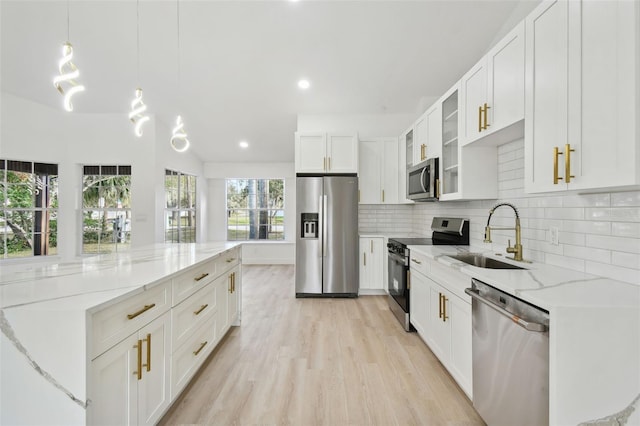 kitchen with appliances with stainless steel finishes, light stone counters, sink, decorative light fixtures, and white cabinetry