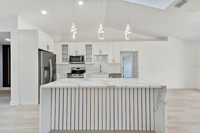 kitchen featuring light stone countertops, appliances with stainless steel finishes, white cabinets, hanging light fixtures, and lofted ceiling