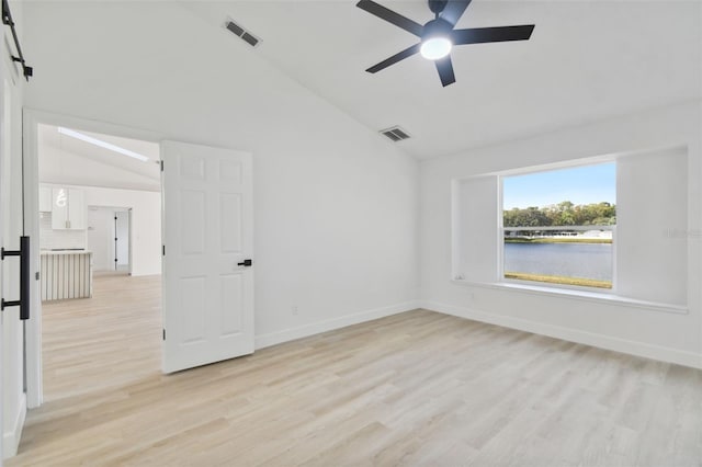 spare room featuring light hardwood / wood-style flooring, vaulted ceiling, ceiling fan, and a water view