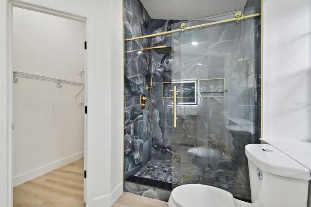 bathroom featuring hardwood / wood-style floors, a shower with door, and toilet