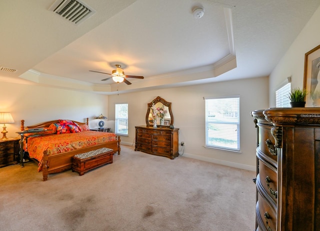 carpeted bedroom with a tray ceiling, ceiling fan, and ornamental molding