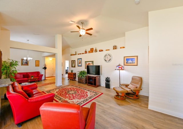 living room with hardwood / wood-style floors, ceiling fan with notable chandelier, and lofted ceiling