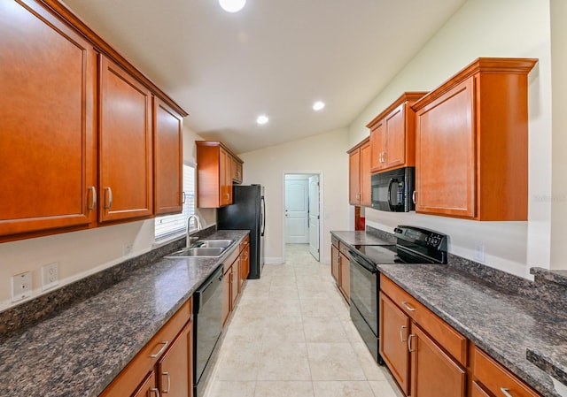 kitchen featuring sink, dark stone counters, lofted ceiling, light tile patterned floors, and black appliances