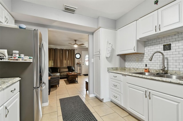 kitchen with stainless steel fridge, tasteful backsplash, ceiling fan, sink, and white cabinets