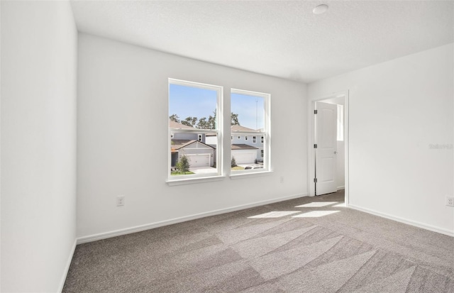 carpeted empty room with a textured ceiling