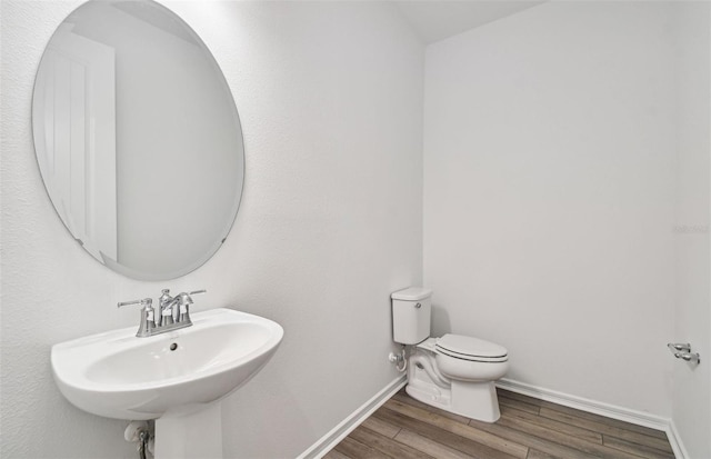 bathroom featuring wood-type flooring, toilet, and sink