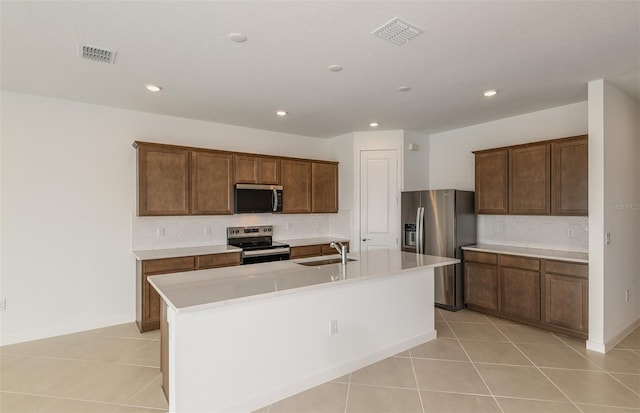 kitchen with stainless steel appliances, sink, a center island with sink, and light tile patterned floors