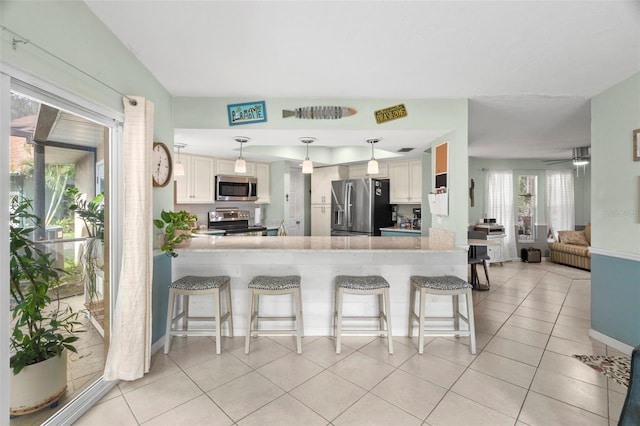 kitchen featuring white cabinetry, a breakfast bar area, kitchen peninsula, and appliances with stainless steel finishes