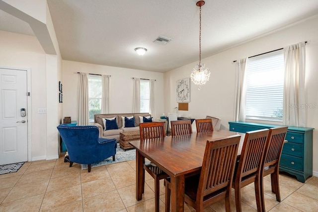 dining area featuring light tile patterned floors, a healthy amount of sunlight, and a notable chandelier