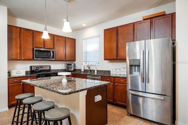 kitchen with a center island, light tile patterned flooring, a textured ceiling, and appliances with stainless steel finishes