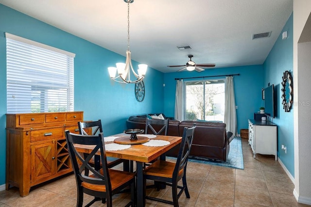 tiled dining space featuring ceiling fan with notable chandelier